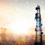 maszt telekomunikacyjny na tle wschodzącego słońca i rozmytych sylwetek miejskich budynków; na pierwszym planie dodane linie symbolizujące przepływ informacji