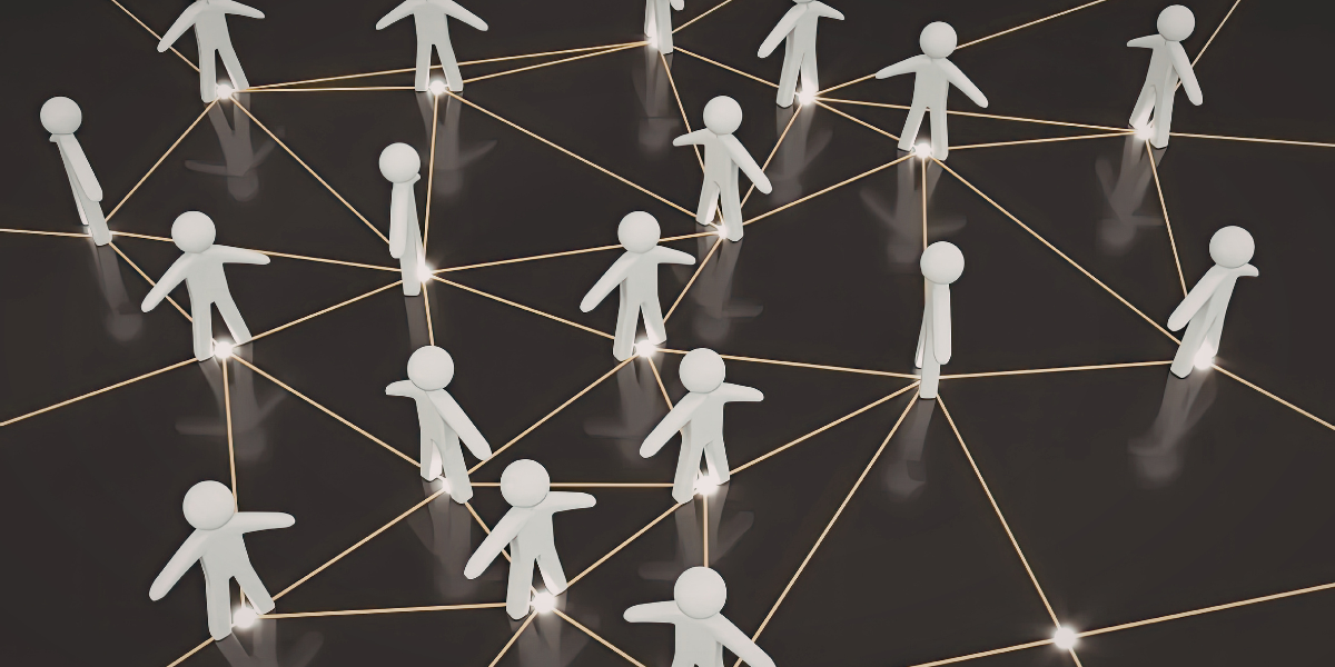 Na ciemnym tle widoczne białe, trójwymiarowe figurki ludzi połączone siecią świecących. Jest to symboliczna ilustracja sieci kontaktów i współpracy.