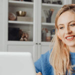 kobieta w słuchawkach, siedząca przed otwartym laptopem, uczestnicząca w spotkaniu online