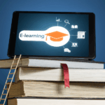 komórka ustawiona poziomo na stosie książek; na wyświetlaczu studencki biret, napis "e-learning" i ikony nawiązujące tematycznie do procesu uczenia się; o stos książek oparta jest drabina