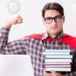 młody mężczyzna w domowej roboty pelerynie superbohatera pręży biceps, a w drugiej ręce trzyma stos książek