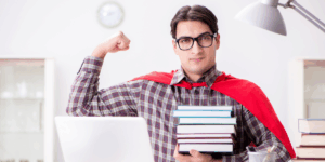 młody mężczyzna w domowej roboty pelerynie superbohatera pręży biceps, a w drugiej ręce trzyma stos książek